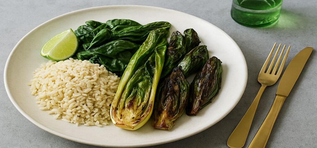 Grüne Grillpfanne mit Pak Choi, Spinat, Chicorée und braunem Basmatireis auf einem weißen Teller, serviert mit Limettenspalte